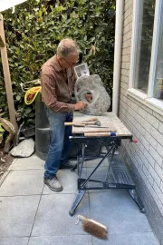 Harry van de Ven bewerkt een serpentijnen beeld met schuurpapier.